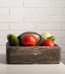 Raw vegetables in a wooden box. Zucchini, tomatoes and cucumbers on a table. Preparation for cooking