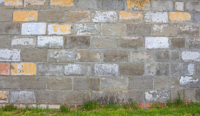 Stara ściana z pomalowanych cegieł. Tło - trawa i mur. 