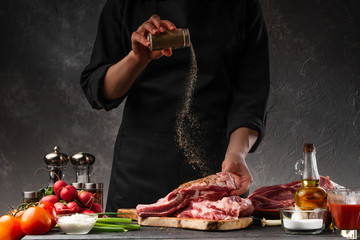 Cooking fresh pork ribs. For roasting and cooking. Chef sprinkles with seasoning for roasting....