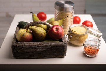 Donation food box with fruit and vegetables, jars with lentil, couscous, wheat on a table