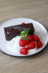 Piece of chocolate and poppy seed cake with whipped cream and strawberries. Selective focus.