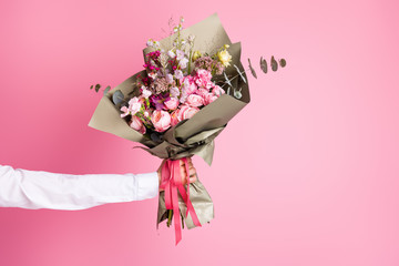 Photo of cropped man arm hold big bright decorated bunch giving girlfriend valentine day romance gift present bouquet composition isolated pink color background - Powered by Adobe