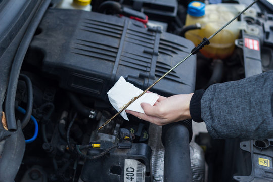 Man checks with oil dipstick and paper towel,the engine oil level of a car Environmental inspection automotive workshop e-mobility control safety oil pollution expert