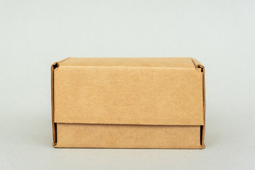 Closed cardboard box on table on white backdrop. Packaging, online shopping and delivery of goods...
