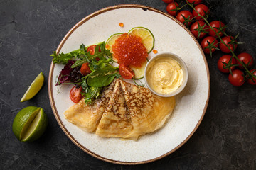 pancakes with red caviar on black background
