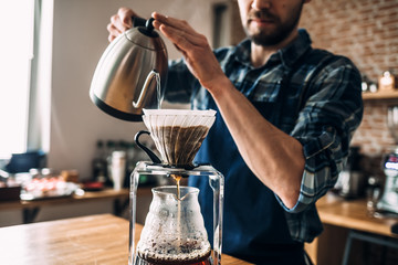 Man prepares coffee in style "pour over" and hario in barista school.