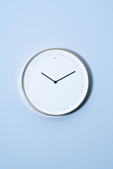A clock hangs on a light blue wall. A wall clock on the wall.