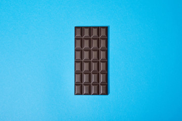 top view of sweet dark chocolate bar on blue background