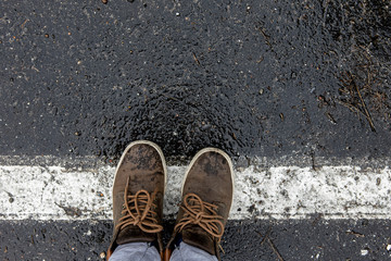 boots of the traveler standing on the pavement on the dividing strip.