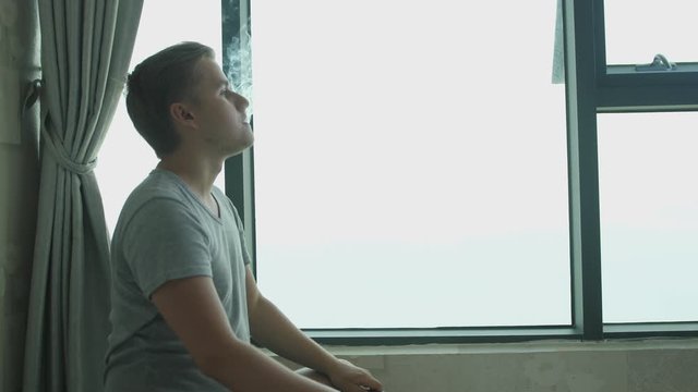 Man smoking Electronic Cigarette Pipe by the Window at Home. slow motion