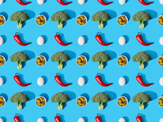 top view of fresh green broccoli, eggs, chili peppers and olives on blue background, seamless pattern