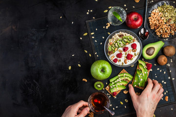 A healthy breakfast of cereals, nuts, yogurt and fruits, water on a dark background. View from above. Bread with avocado. breakfast, there are toast with avocado and nuts. Vegetable proteins.