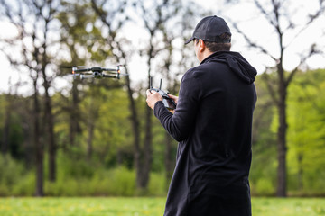 Fototapeta premium Young Man operating a drone with remote control on nature background