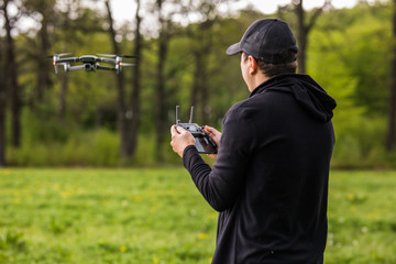 Young Man operating a drone with remote control on nature background