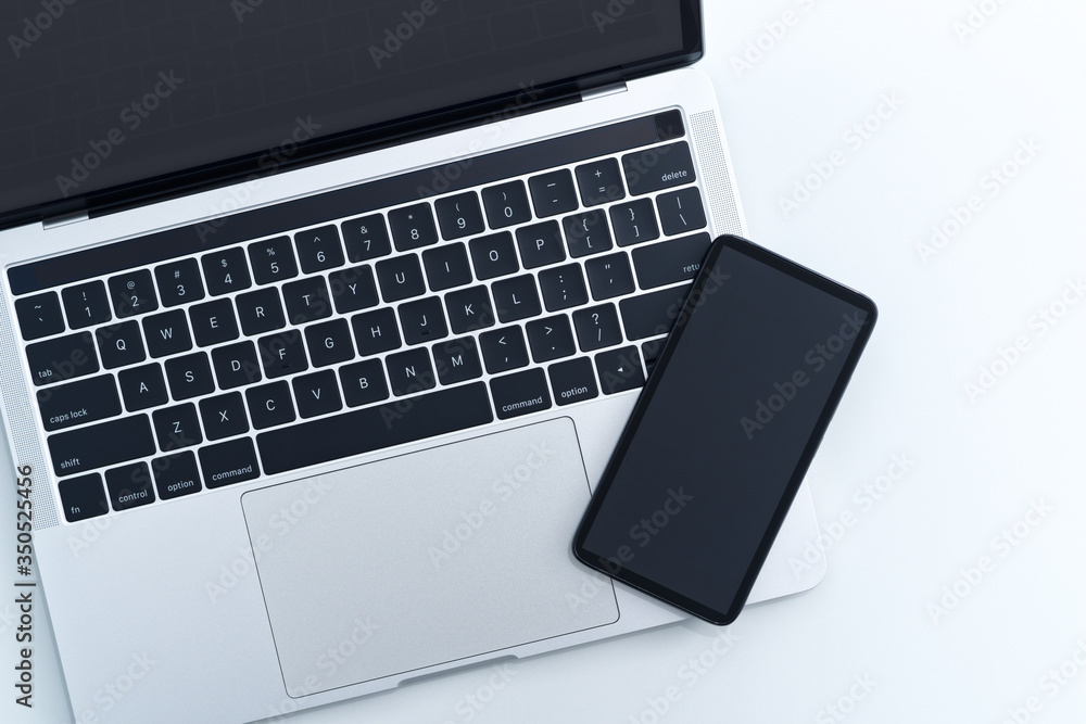 Aufkleber smartphone and laptop computer on white background from above. blank screen.
