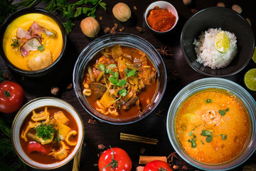 soup, decorated with tomatoes, walnuts and cinnamon on a dark background: chuchvara, lagman, Tom Yam soup, pumpkin soup