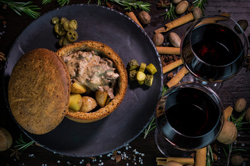 beef Stroganoff in rye bread with red wine, decorated with tomatoes, walnuts and cinnamon on a dark background