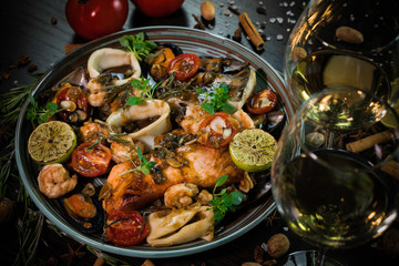company dishes, sea reptiles, fish and squid, decorated with tomatoes, walnuts and cinnamon on a dark background