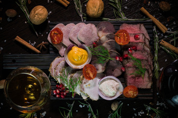 meat delicacies with a glass of white wine, decorated with tomatoes, walnuts and cinnamon on a dark background