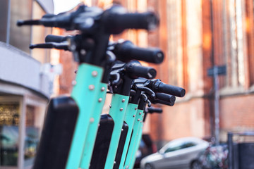 E-scooters or electric scooters are lined up in a row on the street corner in a big city e-mobility e-scooter mobile office means of transport environmentally friendly alternative new cityscape