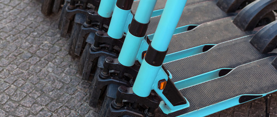 E-scooters or electric scooters are lined up in a row on the street corner in a big city e-mobility e-scooter mobile office means of transport environmentally friendly alternative new cityscape