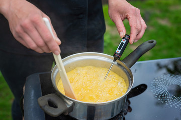 Hands of a female chef prepare citrus syrup. Culinary thermometer.