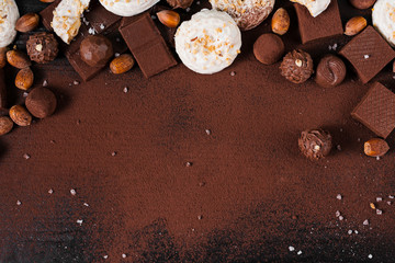 Flat lay chocolate sweets assortment and cocoa powder on pink background with copy space