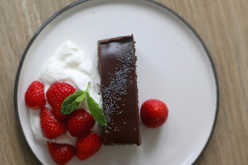 Piece of chocolate and poppy seed cake with whipped cream and strawberries. Top view.