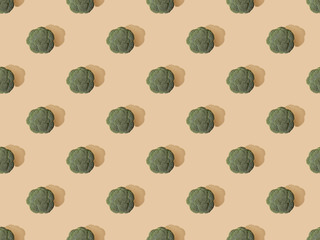 top view of fresh green broccoli on beige background, seamless pattern