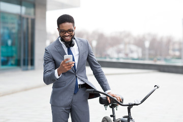 Handsome business man texting on phone holding his bike