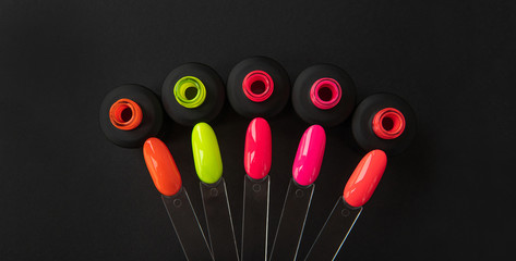 Manicure nail polish samples with bottles in different colors. Nail palette on a dark background  top view