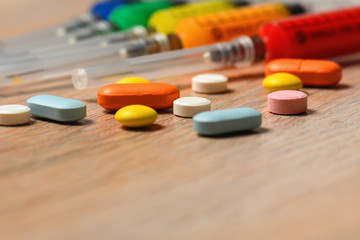 The concept of the treatment options viral infection COVID with copyspace. Colorful syringes and tablets close-up.