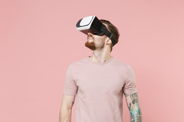 Smiling young bearded tattooed man guy in pastel casual t-shirt posing isolated on pink background studio portrait. People emotions lifestyle concept. Mock up copy space. Looking aside up in headset.