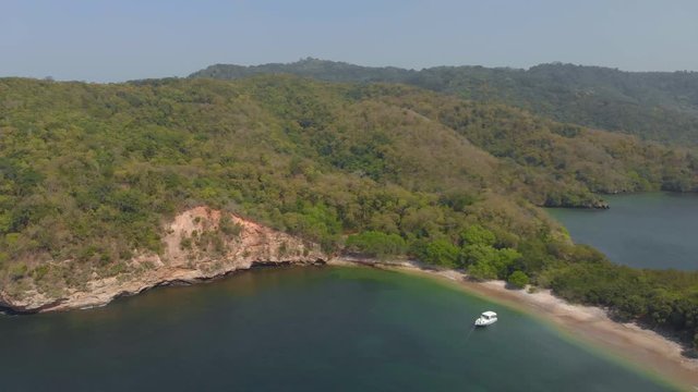 A yacht anchored at La Tinta Bay with waves crashing on the shoreline of this secluded beach on Chacachacare island
