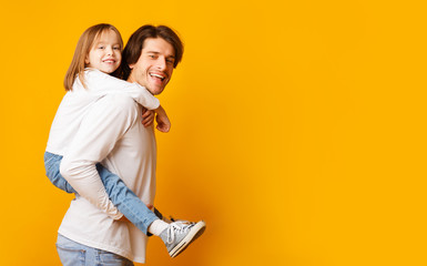 Smiling dad and little girl posing over yellow background