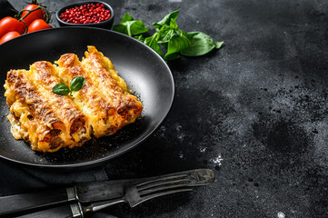 Italian homemade pasta cannelloni with beef and tomato sauce. Black background. top view. Copy space