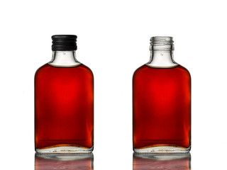 Two mini glass bottles with brown beverage, one with a black cap and another one open.