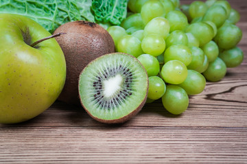 Vegetarian healthy food. Source of protein for vegetarians. Healthy eating: vegetable, kiwi, leaf vegetable, apple, grapes on wooden table.