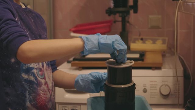 Young girl lift the film spiral out of the tank and eximining the negative.