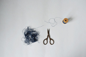 Blue tangle thread spool and scissors over white