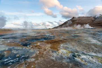 Hverarond geothermal area in Myvatn, Iceland. Steam vents and hot pools, muddy hot soil, sulfur smoke and colorful textures and patterns during blue hour.
