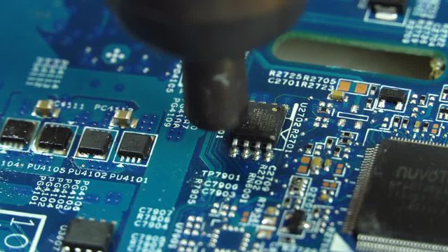 Hot air soldering. A master solders a mv workshop of a radio component using a soldering hair dryer.