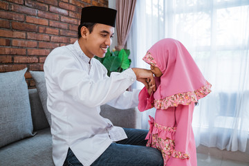 Obraz premium portrait of daughter kissing hands to his father apologize on eid mubarak