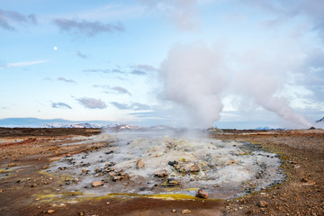 Hverarond geothermal area in Myvatn, Iceland. Steam vents and hot pools, muddy hot soil, sulfur smoke and colorful textures and patterns during blue hour.