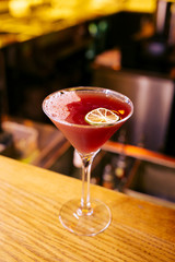 Red fruit coktail on the wooden table with  a slice of lime at the restaurant. Summer beverage.