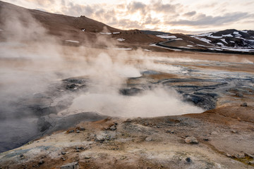 Hverarond geothermal area in Myvatn, Iceland. Steam vents and hot pools, muddy hot soil, sulfur smoke and colorful textures and patterns during blue hour.