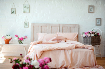 Stylish room interior with big comfortable bed in pink color with lots of flowers. Interior bedroom furniture concept. Cozy Pink Bedroom corner. Beautiful and bright bedroom loft style.