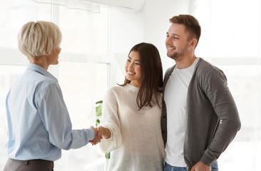 Psychologist Handshaking With Happy Couple After Therapy Standing In Office