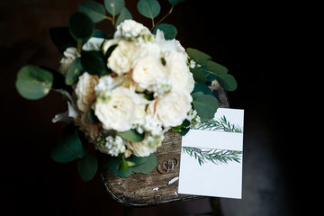 The bouquet and the rings with empty space invitation on the wooden table. Wedding details.