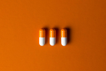 The concept of positive. Three orange capsules on an orange background. Capsules lie in a row in...